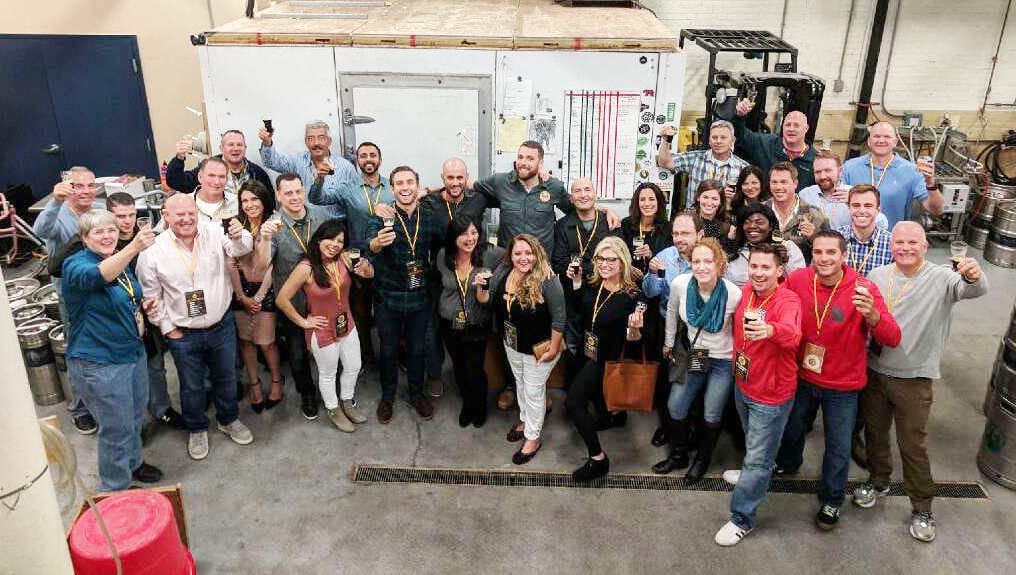 A large corporate group poses for a picture on their private City Brew Tour