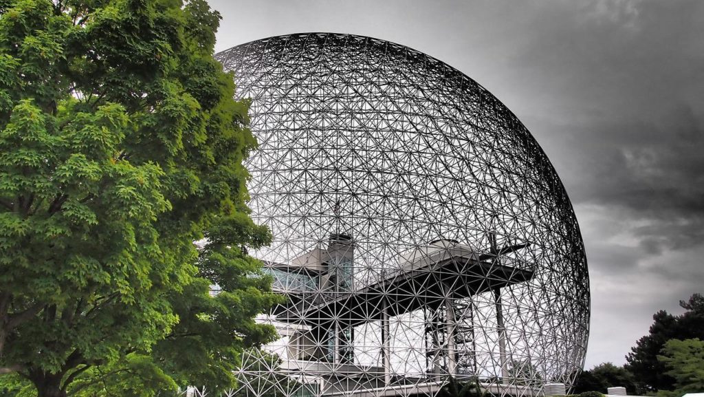 The iconic Biosphère Environment Museum in Montreal, captured against a dramatic sky. This geodesic dome, originally designed by Buckminster Fuller for Expo 67, stands surrounded by lush greenery, emphasizing its role as a symbol of sustainability and environmental education in the heart of the city.