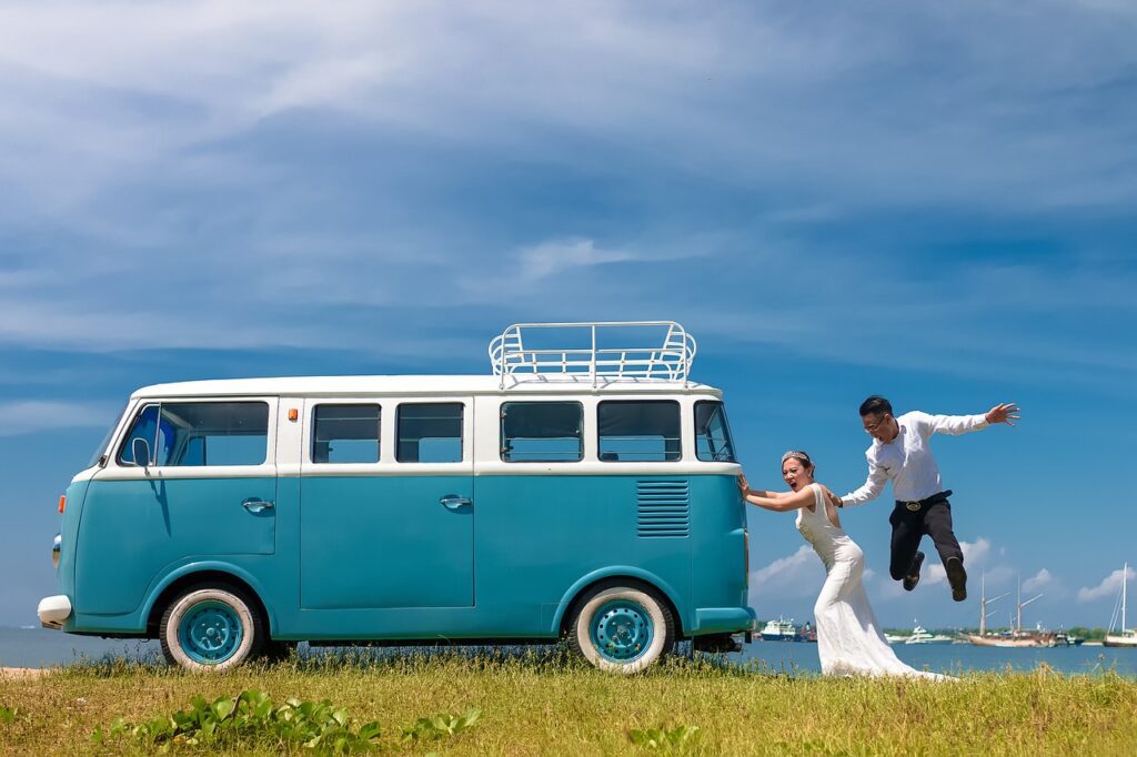 A couple having fun near a vintage blue van, perfect for a scenic bachelorette party road trip or photo shoot.