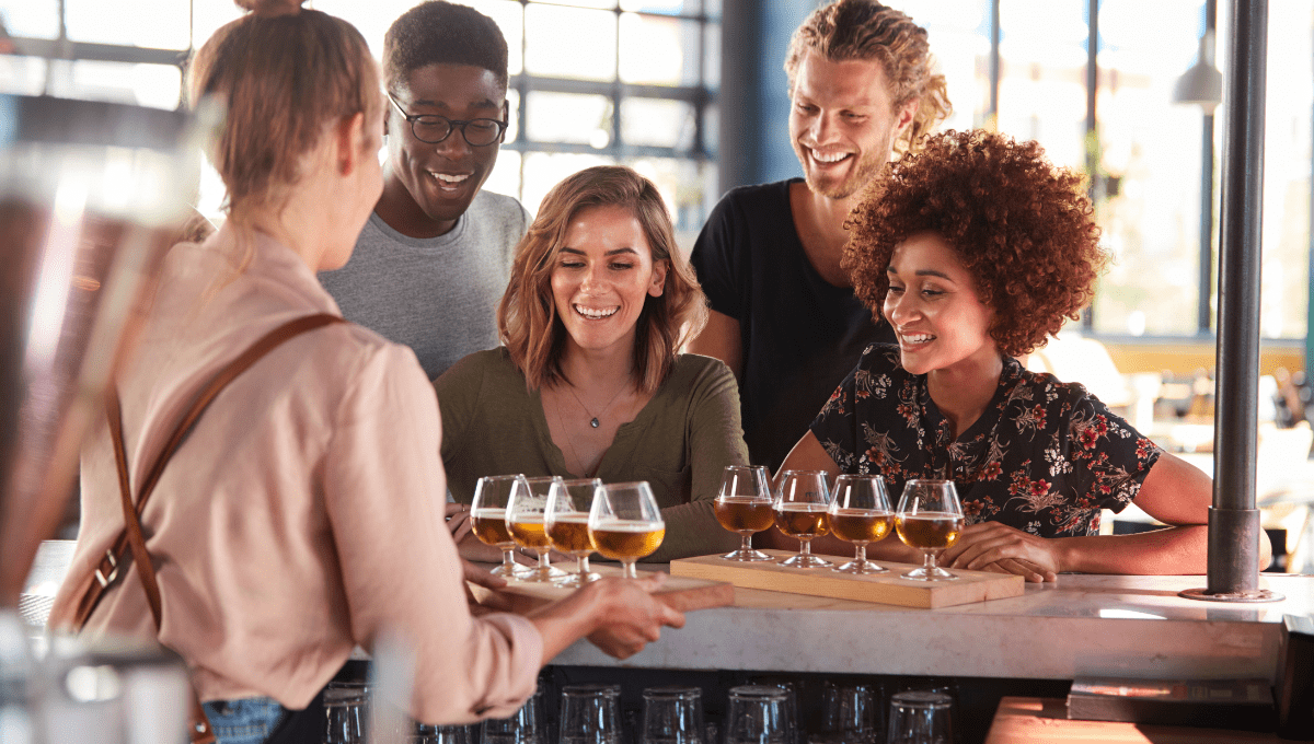 Group of friends enjoying a guided beer tasting with various beer styles on a flight board during a craft beer tour in Montreal