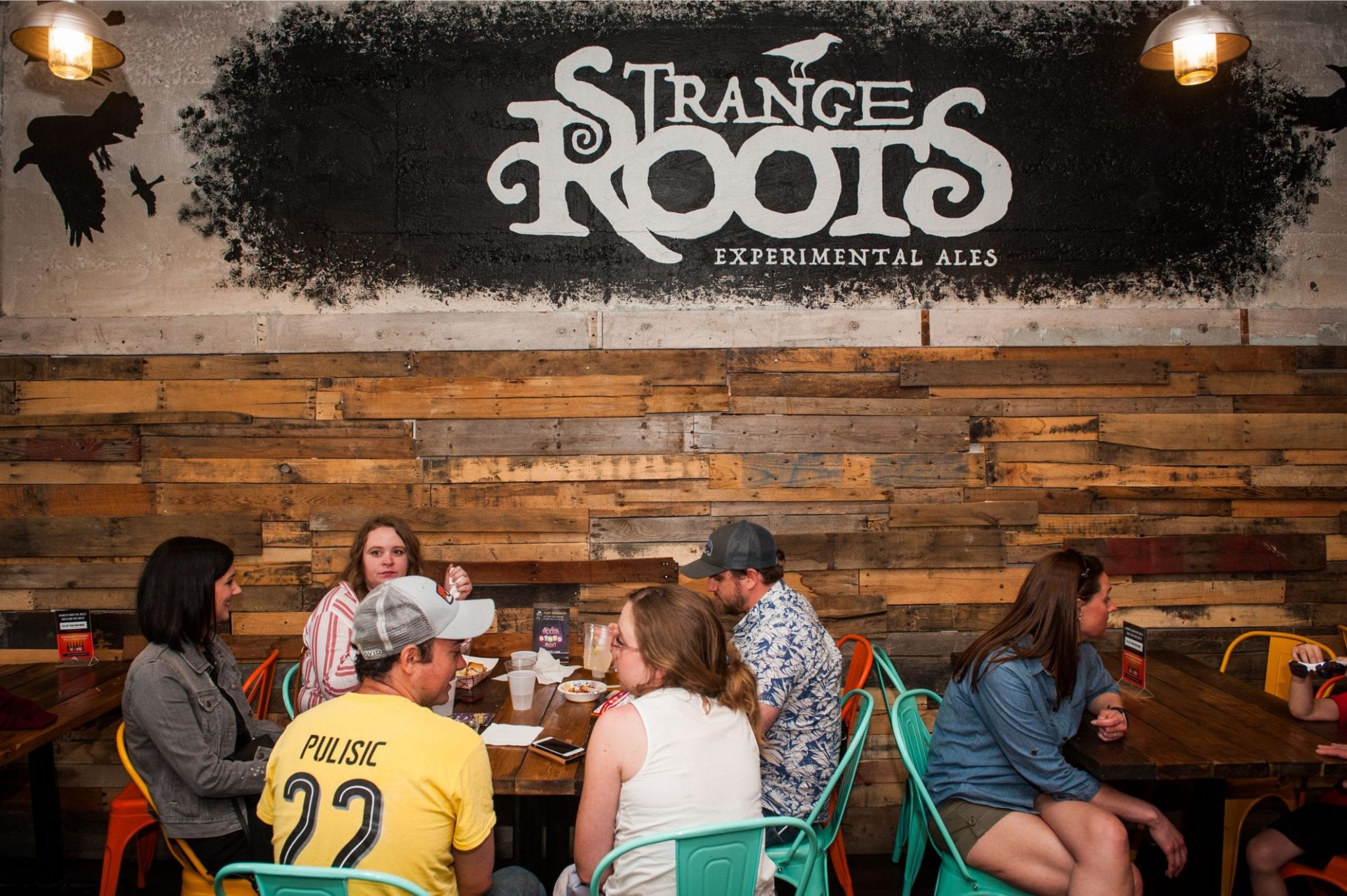 Guests sit around tables in Strange Roots' taproom