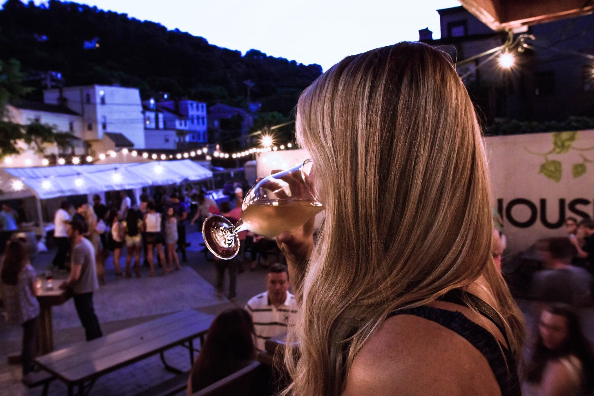 A woman enjoys a pint of beer in Grist House's biergarden in Pittsburgh, PA