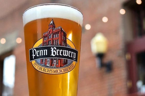A full pint of Penn Brewery beer in front of the brewery's brick exterior in Pittsburgh, PA
