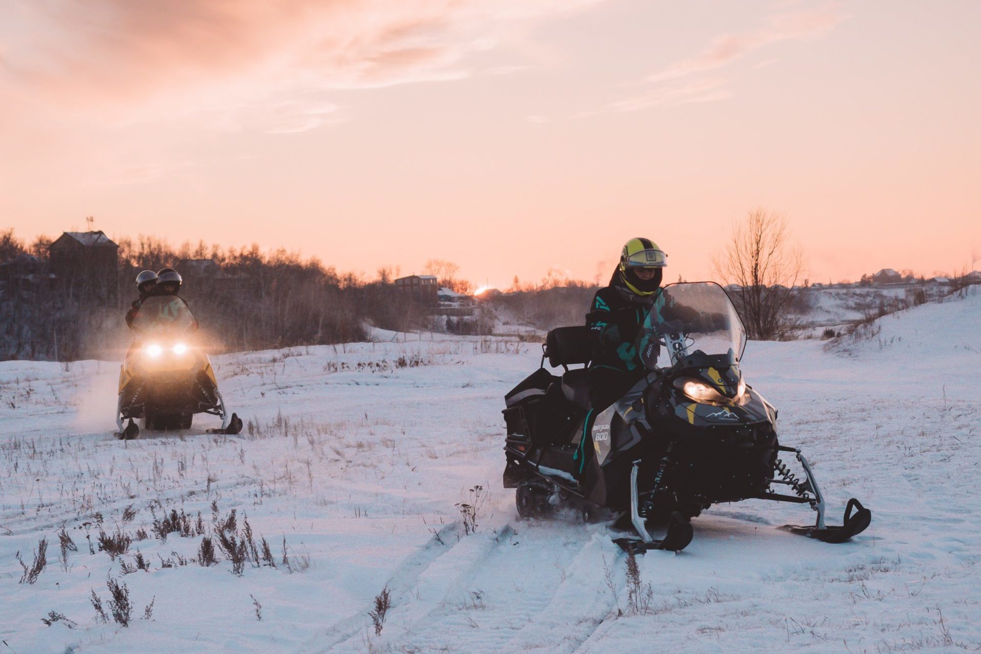 Two people riding snowmobiles